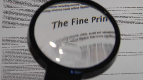 Magnifying-glass-passes-over-paper-to-reveal-the-words-The-Fine-Print