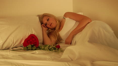Eine-Frau-Erwacht-Und-Findet-Blumen-Und-Eine-Herzförmige-Schachtel-In-Ihrem-Bett