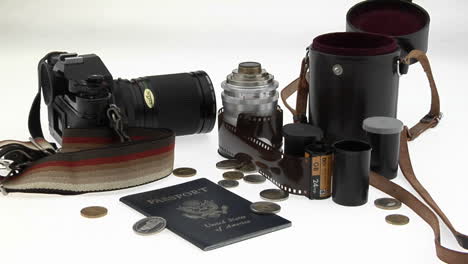 A-passport-coins-camera-and-equipment-sit-on-a-white-table
