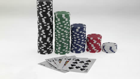 Stacks-of-poker-chips-sit-in-a-row-arranged-by-value-behind-a-deck-of-playing-cards