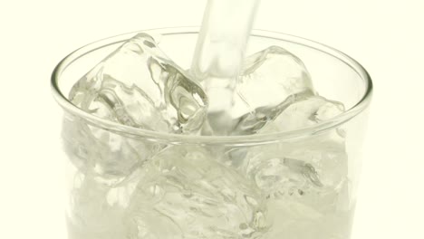 Klare-Kohlensäurehaltige-Flüssigkeit-Wird-über-Eis-In-Ein-Glas-Gegossen