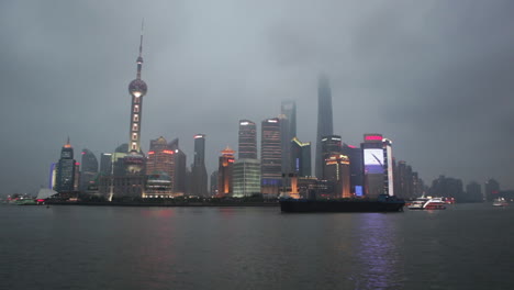 Die-Nachtskyline-Von-Shanghai-China-Mit-Flussverkehr-Im-Vordergrund
