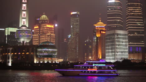 Die-Lebendige-Nachtskyline-Von-Shanghai-China-Mit-Flussverkehr-Im-Vordergrund