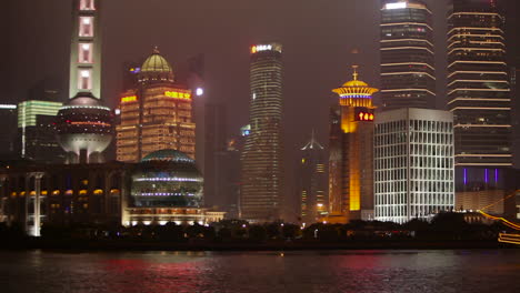 Die-Lebendige-Nachtskyline-Von-Shanghai-China-Mit-Flussverkehr-Im-Vordergrund-Und-Beleuchtetem-Großsegler