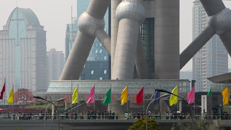 Chinese-people-walk-at-the-base-of-a-large-modern-tower-on-the-Pearl-River-in-Shanghai