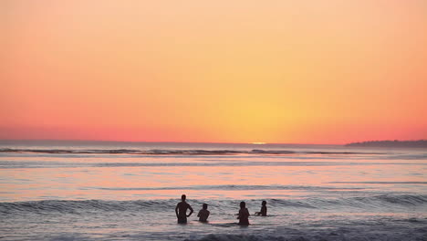 People-gather-at-the-ocean-at-sunset
