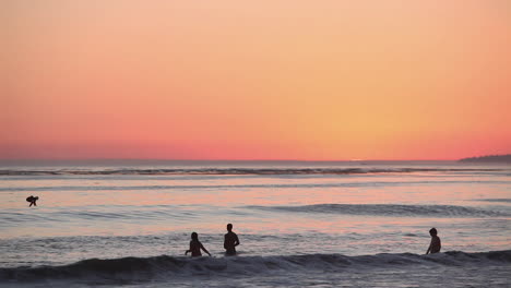 People-gather-and-play-in-the-ocean-at-sunset