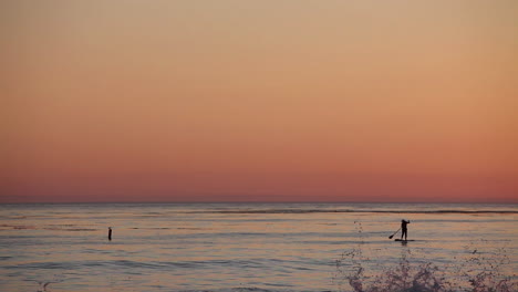 A-paddle-boarder-rows-across-the-ocean-at-sunset-1