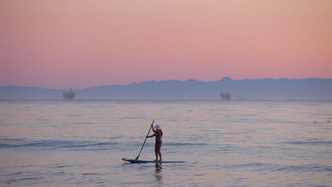A-paddle-boarder-rows-across-the-ocean-at-sunset-2