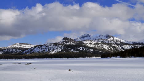 Timelapse-of-clouds-blowing-over-frozen-lake-and-mountains