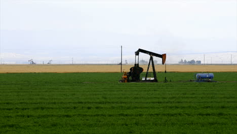 Zeitraffer-Einer-Ölquelle,-Die-Mitten-In-Einem-Ackerfeld-Pumpt