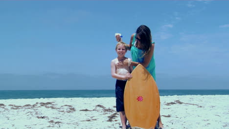 A-woman-rubs-sunscreen-on-a-boy-at-the-beach