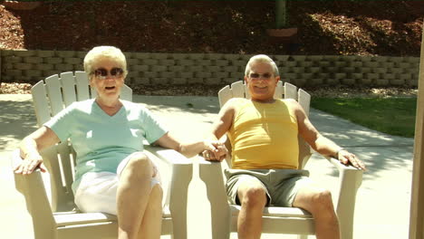 A-husband-and-wife-sit-in-lawn-chairs-holding-hands
