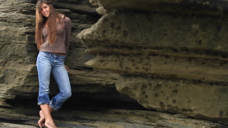 A-young-woman-leans-against-a-rock-wall-