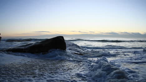 A-hand-held-camera-captures-waves-rolling-on-to-a-beach-just-after-sunset-1