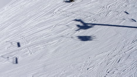 The-shadows-of-a-ski-lift-in-operation-against-a-snow-covered-mountainside-