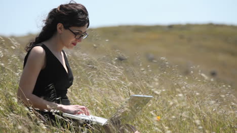 A-woman-using-a-laptop-sits-in-a-field-2