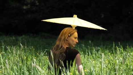 Eine-Junge-Frau-Mit-Regenschirm-Steht-Im-Hohen-Gras