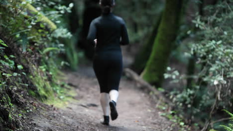 A-woman-jogs-on-a-path-in-a-wooded-area