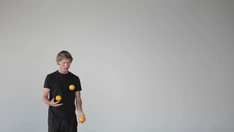 A-man-juggles-three-orange-balls-using-both-his-hands-and-his-legs
