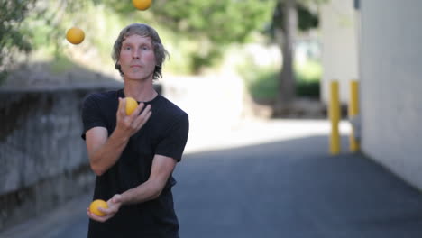 A-man-does-a-juggling-act-with-four-orange-balls