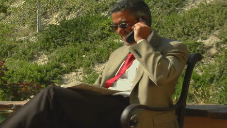 A-businessman-speaks-on-a-cell-phone-from-a-patio