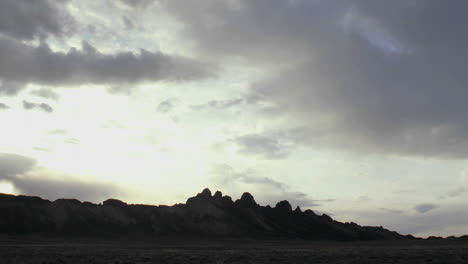 Hauchdünne-Grau-weiße-Wolken-Ziehen-Zur-Goldenen-Stunde-über-Einen-Berggipfel