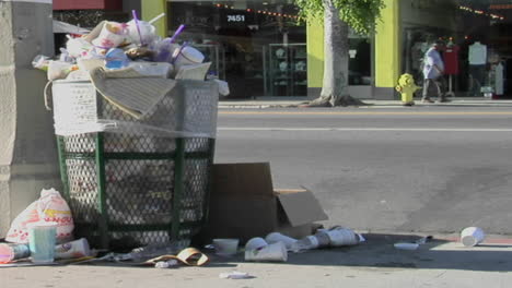 Trash-spills-out-of-an-overfilled-trash-can-on-a-city-street