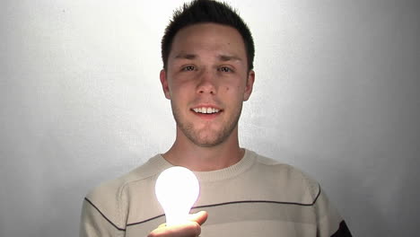 A-young-man-gazes-at-a-compact-fluorescent-light-bulb-as-it-lights-1