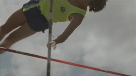 A-young-man-does-a-pole-vault-lands-on-a-mat-and-stands-up-smiling