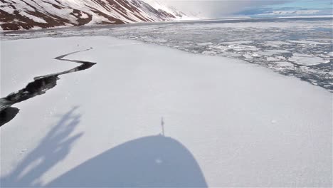 Sombra-De-Un-Barco-Moviéndose-A-Través-Del-Hielo-Marino-En-Lomfjorden-En-El-Archipiélago-De-Svalbard,-Noruega