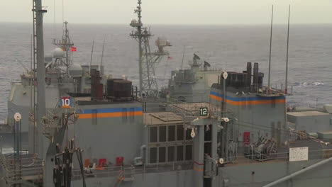 Three-Navy-Ships-Travel-Alongside-One-Another-During-A-Replenishment-At-Sea-Exercise