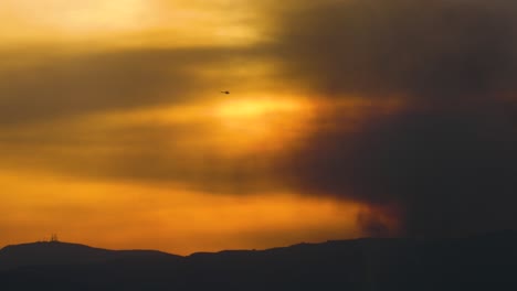 Das-Thomas-feuer-Brennt-Bei-Sonnenuntergang-In-Den-Hügeln-über-Ojai-Kalifornien-Mit-Wassertropfendem-Helikopter-Vorbei