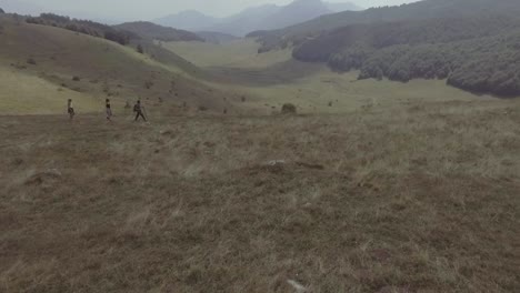 Drone-Aerial-Of-Three-Hikers-Walking-Over-The-Lukomir-Village-Highlands-And-Mountains-Of-Bosnia-Eastern-Europe