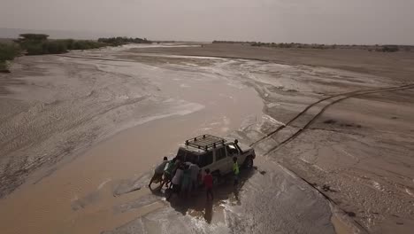 Antenne-Von-Menschen,-Die-Einen-4x4-Jeep-Aus-Einem-Schlammigen-Fluss-In-Den-Wüsten-Von-Dschibuti-Oder-Somalia-Afrika-Schieben