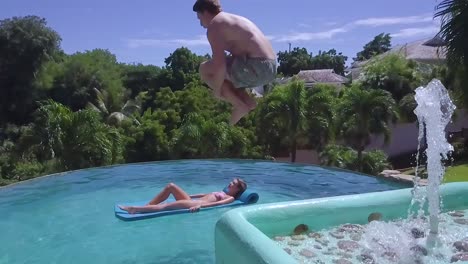 Super-Slow-Motion-Shot-Of-A-Man-Doing-A-Cannonball-Dive-Into-A-Pool-And-Upsetting-A-Woman-Floating-There