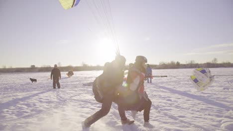 Two-People-Paraglide-On-A-Snowy-Field-In-Latvia