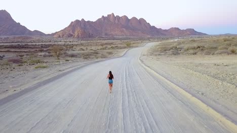Antena-Sobre-Una-Mujer-Corriendo-Por-Un-Camino-De-Tierra-Cerca-De-Spitzkoppe,-Namibia
