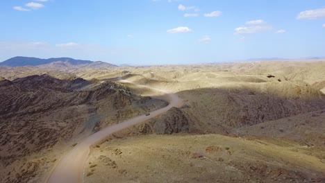 Excellent-Aerial-Of-A-4X4-Jeep-Safari-Vehicle-On-A-Dirt-Road-Through-The-Mountains-Of-The-Namib-Desert-In-Namibia-Africa-1