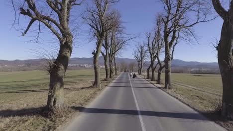 Un-Hombre-Y-Una-Mujer-Corren-Por-El-Medio-De-Una-Carretera-En-Eslovenia-En-Esta-Toma-Aérea-De-Un-Dron