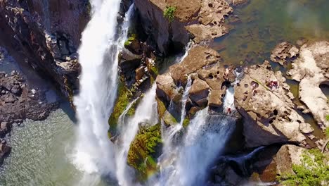 Antena-De-Un-Hombre-Y-Una-Mujer-Sentados-En-La-Cascada-De-La-Piscina-Del-Diablo-En-Victoria-Falls,-Zambia-2