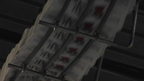 A-fast-zoom-into-newspapers-moving-along-the-top-of-an-assembly-line
