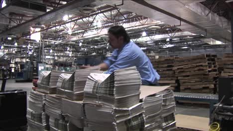 A-worker-stacks-newspapers-at-a-printing-factory