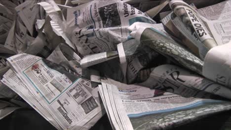 Pan-across-old-crinkled-newspapers-sit-in-a-recycling-bin-in-a-factory