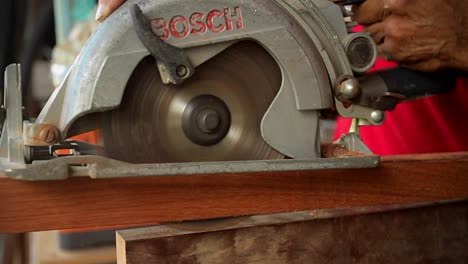 A-circular-saw-cuts-through-wood-at-a-workbench