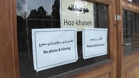 Schilder-An-Einem-Fenster-Im-Iran-Einer-Liest-Hozkhaneh,-Die-Anderen-Verbieten-Das-Fotografieren-Und-Bitten-Die-Besucher,-Die-Tür-Zu-Schließen