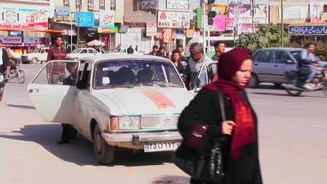 Men-walk-down-a-busy-city-street-in-Iran-
