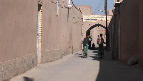 Zwei-Kinder-Fahren-Mit-Dem-Fahrrad-Durch-Eine-Alte-Gasse-Im-Iran