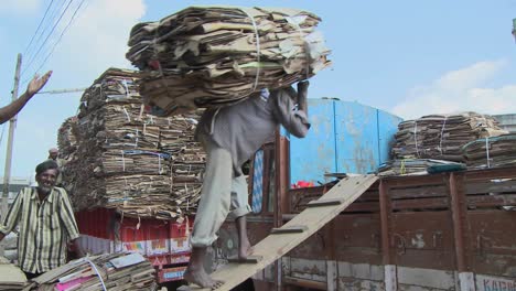 An-older-man-carries-a-heavy-load-of-cardboard-up-a-ramp