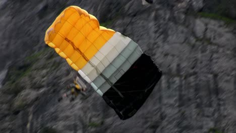 A-man-paraglides-through-a-mountain-pass-near-a-waterfall